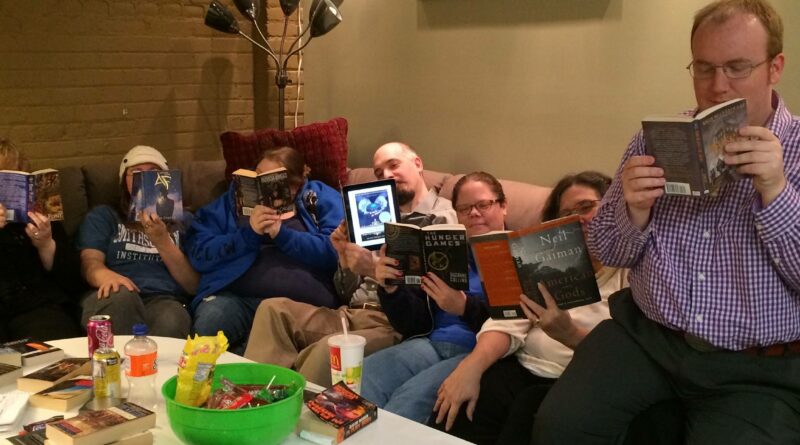 A group of people pretending to read a book and ignoring the camera person entirely